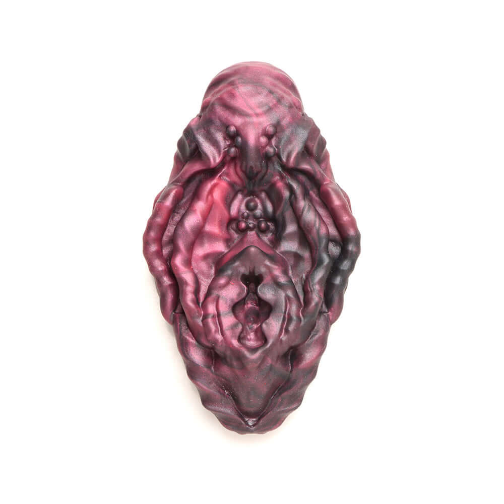 Alien vulva silicone grinder in red and black with textured grooves for unique non-penetrative pleasure.