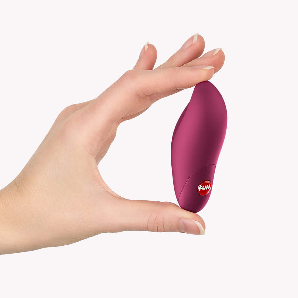Fun Factory Charme Rechargeable Bullet Vibrator Wine Red held in hand for scale and portability demonstration.