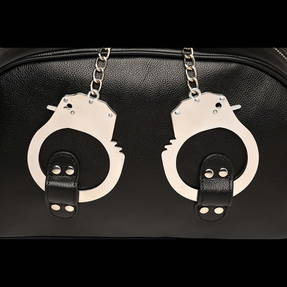 Close-up of metal handcuff handles on a stylish faux leather travel bag, perfect for adventure and fun.