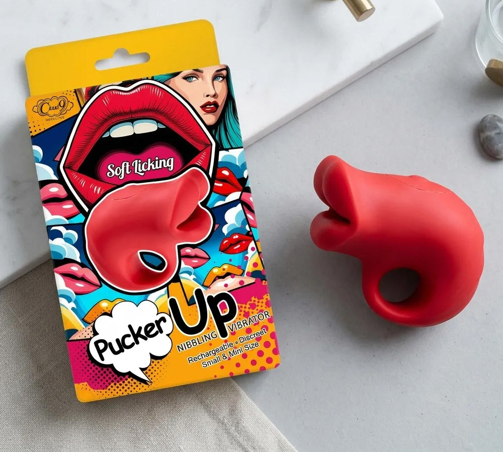Pucker Up Lips With Ergonomic Finger Hold Red Vibrator next to its colorful packaging on a flat surface.