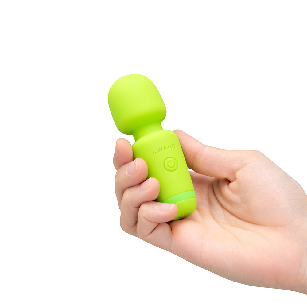 Le Wand Essentials Mini Wand Vibe Pocket-sized Vibrator held in a hand, showcasing its compact design and vibrant green color.