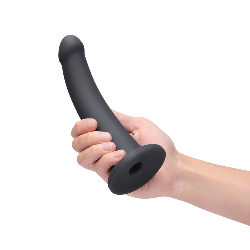 B-Vibe Essentials 7 Inch Smooth Silicone Dildo Black held in hand, showcasing its sleek design and smooth texture.