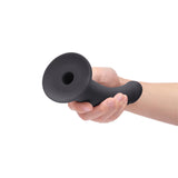 B-Vibe Essentials 7 Inch Smooth Silicone Dildo Black held in hand on a white background.