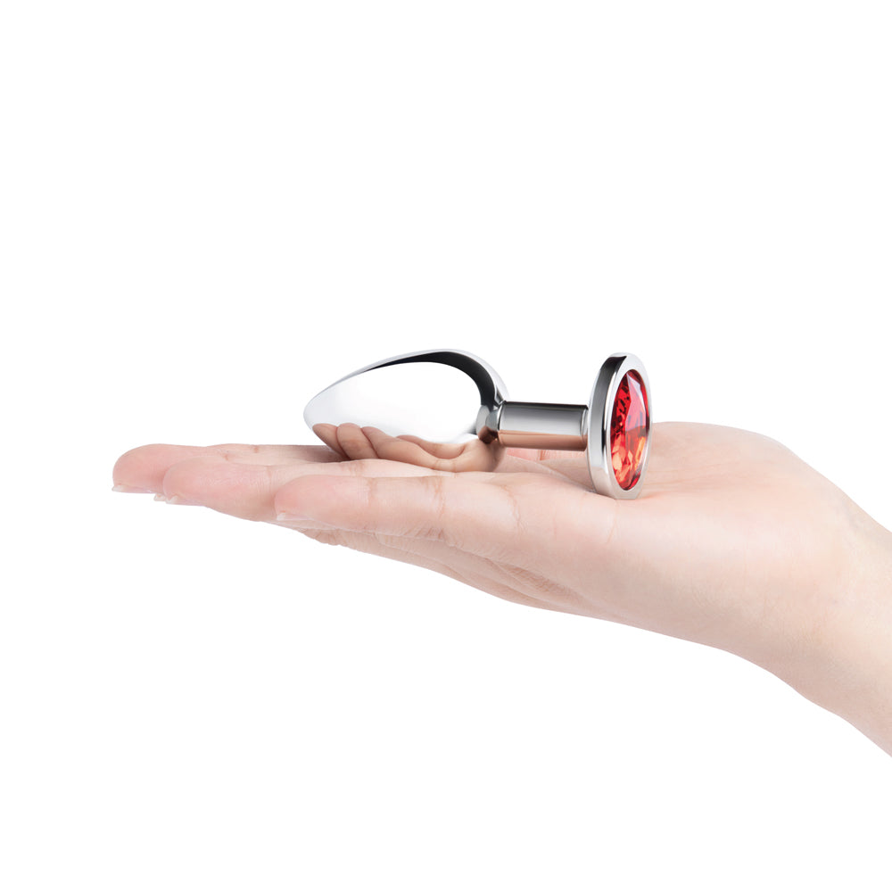 b-Vibe Essentials 3.25 Inch Steel Jewel Butt Plug Red on a hand, showcasing its elegant design and sparkling red jewel base.