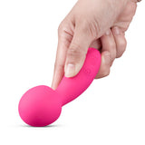 Hand holding Together Spark On The Go Mini Wand Vibrator, a compact and playful pink massager.