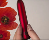 Poppy Red Rechargeable Bullet Vibrator held beside vibrant poppy flowers.