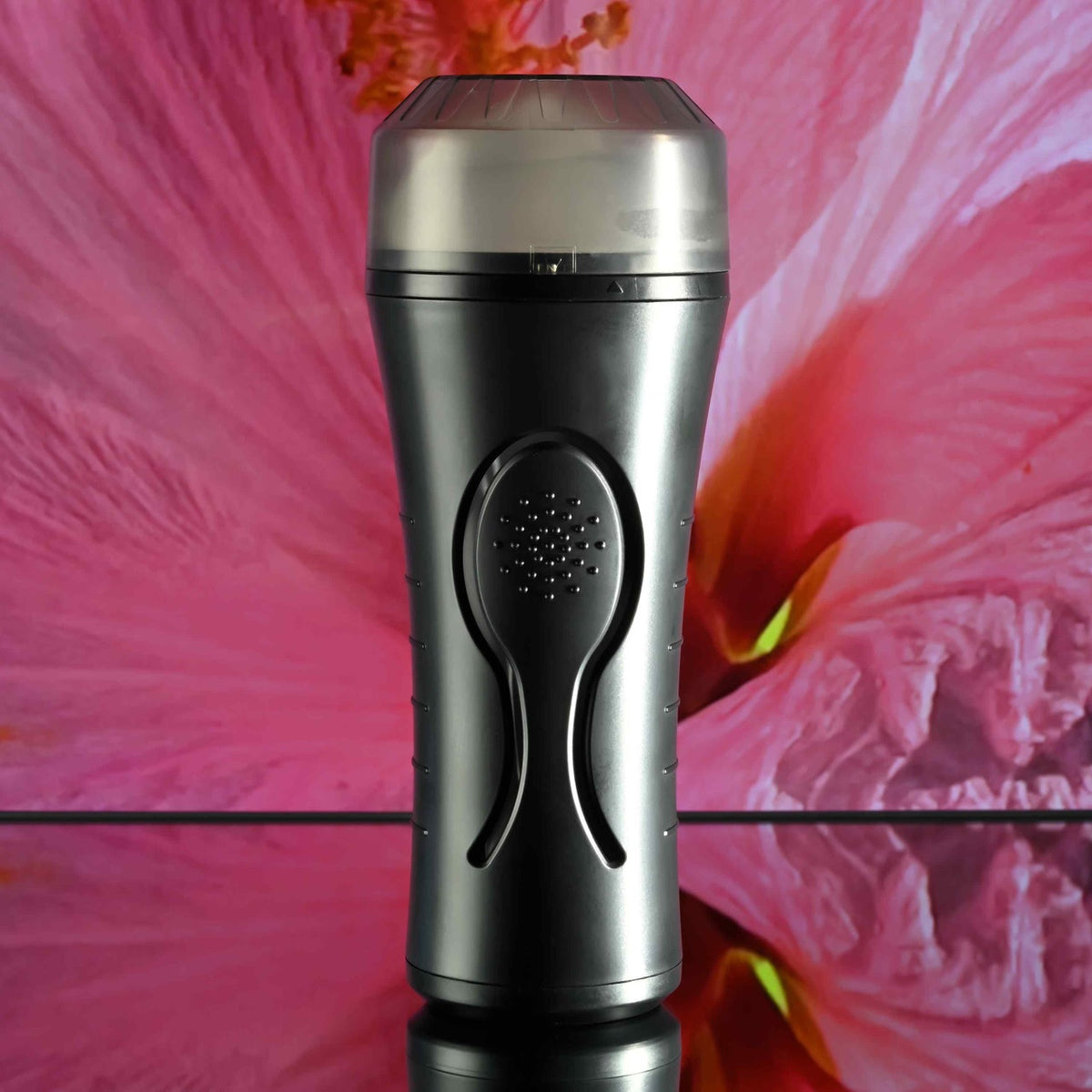 Zero Tolerance Hold Tight Vibrating Stroker Black on reflective surface with vibrant floral background.