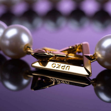 UPKO "Moist Eyes" Pearl Bracelet Handcuffs with golden clasp on reflective surface