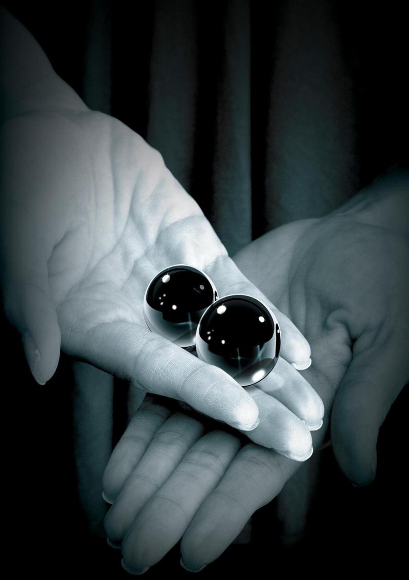 Fetish Fantasy Glass Ben-Wa Ball 1.25 inch Black held in hands, showcasing the smooth design and luxurious material.