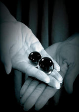 Fetish Fantasy Glass Ben-Wa Ball 1.25 inch Black held in hands, showcasing the smooth design and luxurious material.