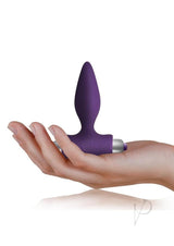 Petite Sensations Silicone Vibrating Butt Plug Purple resting in a hand showcasing its compact size and design.