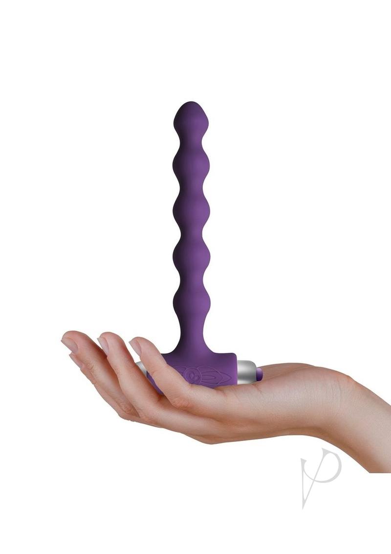 Petite Sensations Pearls Silicone Vibrating Anal Bead Purple in a hand, showcasing its slim design and vibrant color.
