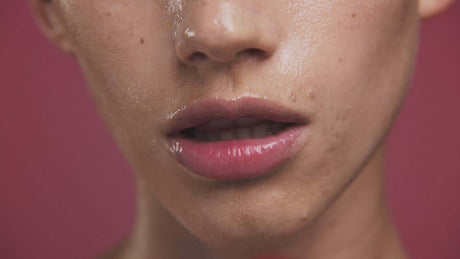 Close-up of a person's lips with a glossy sheen, highlighting natural beauty and skin texture.
