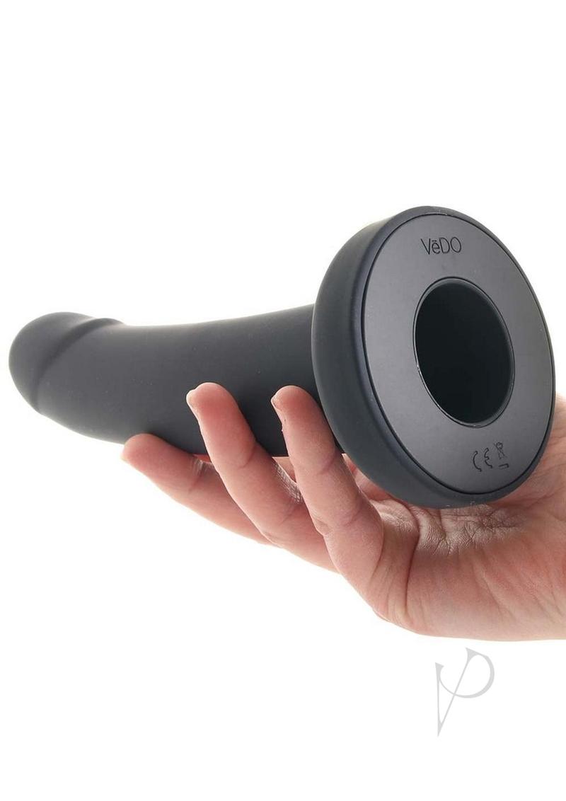 VeDO Strapped Vibrating Strap On Remote Just Black held in hand showcasing sleek design and smooth silicone material.