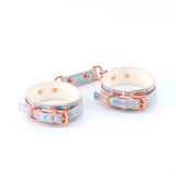 Cosmo Bondage Wrist Cuffs Rainbow showcasing a holographic shine with rose gold hardware for stylish intimate play.