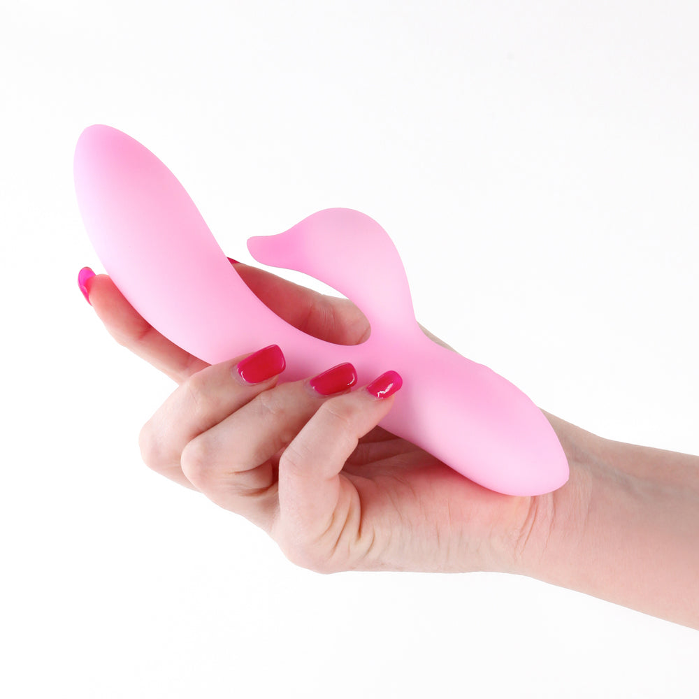Image of NS Novelties Pure Dawn Rabbit Vibrator Pink held in a hand with manicured nails.