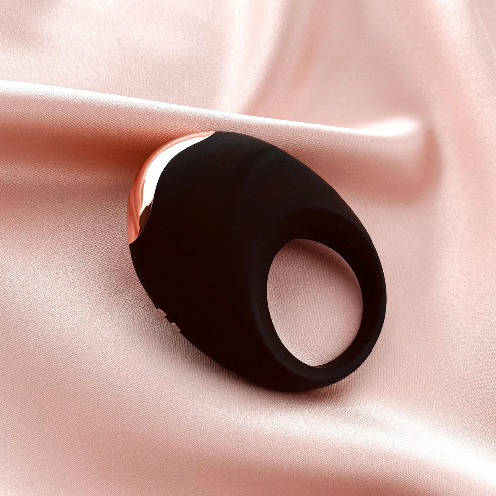 Edonista Luca Vibrating Penis Ring Black on soft satin fabric, showcasing its sleek design and comfortable fit.