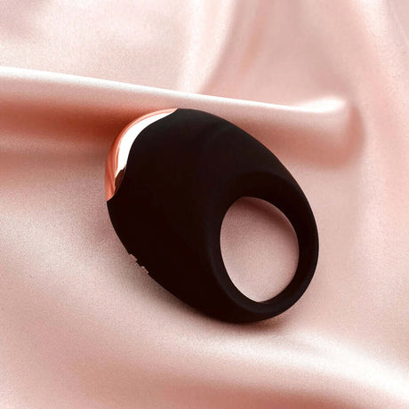Edonista Luca Vibrating Penis Ring Black on soft satin fabric, showcasing its sleek design and comfortable fit.