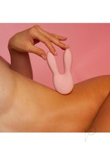 Hear Me Baby Silicone Clitoral Stimulator Baby Pink nestled on a woman's arm against a pink background.