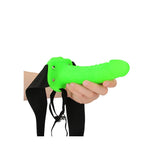 Ouch Realistic 7 inch Strap-on Harness Glow In The Dark held in hand, showcasing its fluorescent green design.