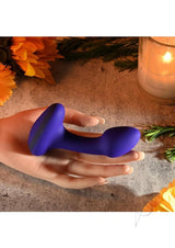 Gender X Anybody's Plug Silicone Vibrating Butt Plug Blue resting on a hand with flowers and a candle.