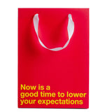 Lower Your Expectations Color Gift Bag Red featuring bold message on red background.