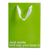 Just Smile & Say You Love It Color Gift Bag Green on display with white text for gift giving humor.