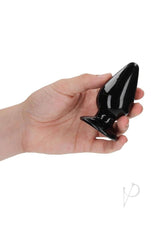 RealRock Crystal Clear 3.5 Inch Anal Plug Black being held in hand, showcasing its tapered design and transparency.