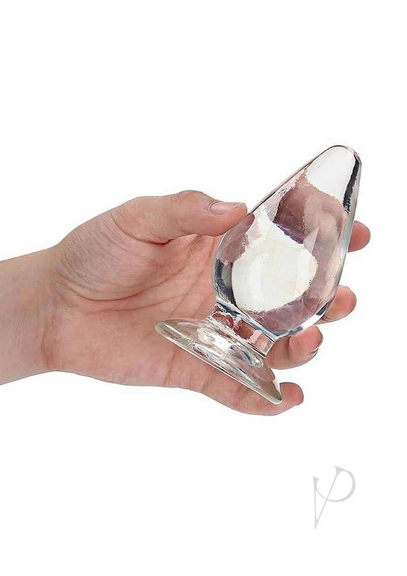 Hand holding the RealRock Crystal Clear Anal Plus 4.5in Clear, a see-through anal plug for comfortable exploration.
