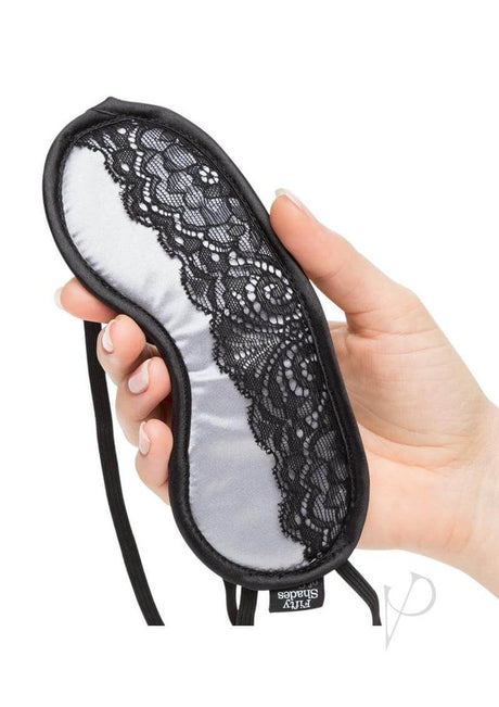 Fifty Shades of Grey Play Nice Satin and Lace Blindfold held in hand, showcasing silver satin with black lace detailing.