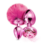 Nixie Metal Butt Plug Set Pom Pom Jewel Pink Metallic featuring a soft pink pom pom and jewel inlaid plugs.