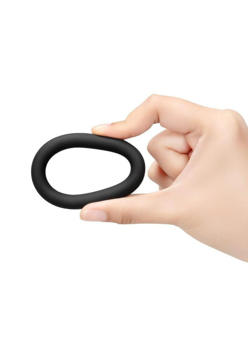 B-Vibe Snug Ring Thick Silicone Cock Ring 3 Pack Black held in hand displaying its soft texture and ergonomic design.