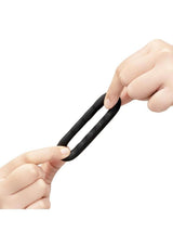 B-Vibe Flex Ring Tread Silicone Cock Ring Black being held and stretched by hands.