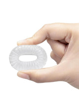 Hand holding B-Vibe Stretch Tech Swirl Ultra Stretchy Cock Ring Clear, showcasing its flexible design.