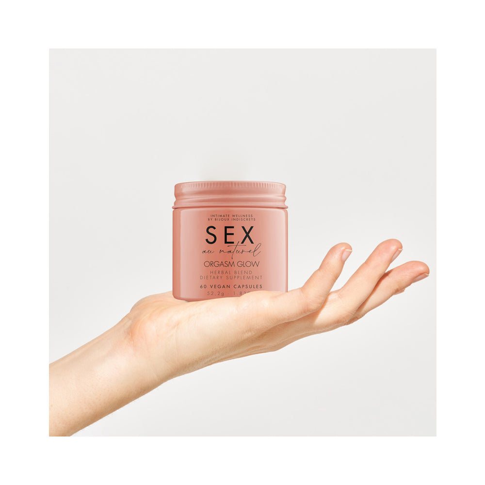 Bijoux Indiscrets Orgasm Glow Supplement 60 Capsules in a hand, promoting sexual wellness and balance.