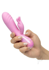 Holding the Aura Thrusting Bunny Silicone Rabbit Vibrator Pink, showcasing its playful design and features.