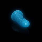 Realrock Glow In The Dark Slim Dildo 6 inches Neon Blue with luminous glow effect on a black background.