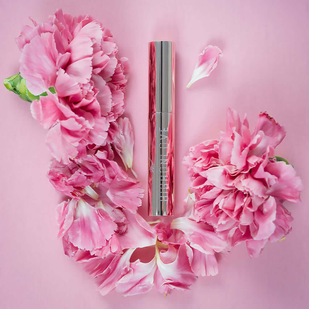 HighOnLove Mini Lip Gloss surrounded by pink flowers on a soft pink background.