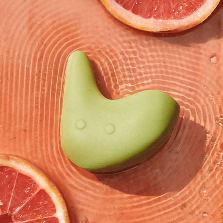 Ohnut Kiwi Vibrating Personal Massager on a textured surface with citrus slices around it.