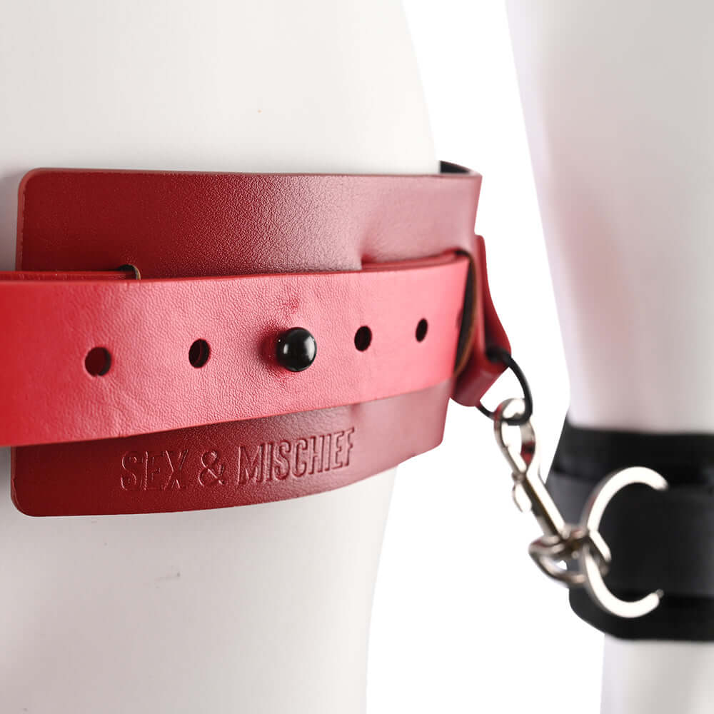 Close-up of Sex & Mischief Exs & Ohs Bound and Belted red faux leather restraint belt with metal clips.