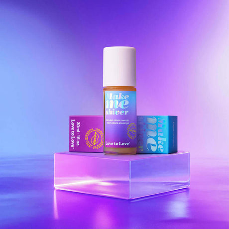 Love to Love Make Me Shiver Frenulum Stimulating Serum 1 Oz displayed on a lit platform with product packaging.