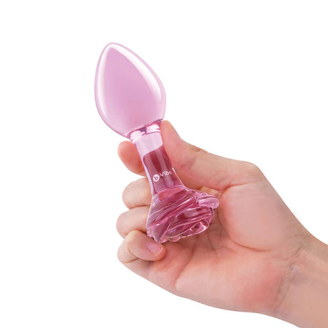 b-Vibe Glass Pink Roses Training Plug Set held in hand, featuring a sleek pink design and rose-detailed base.