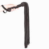 Prowler RED Leather Suede Flogger Black held in hand, showcasing premium BDSM accessory for impact play.