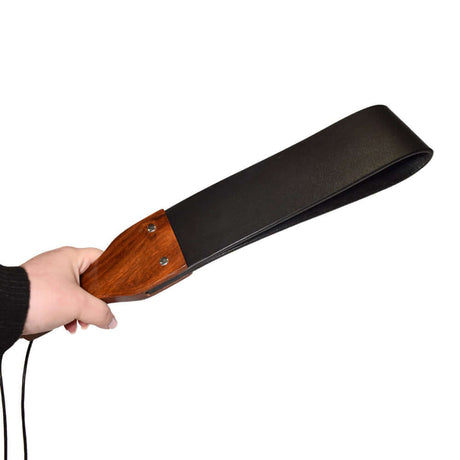Prowler RED Leather & Wood Flapper Paddle held in hand showcasing its sleek design and sturdy wooden handle.