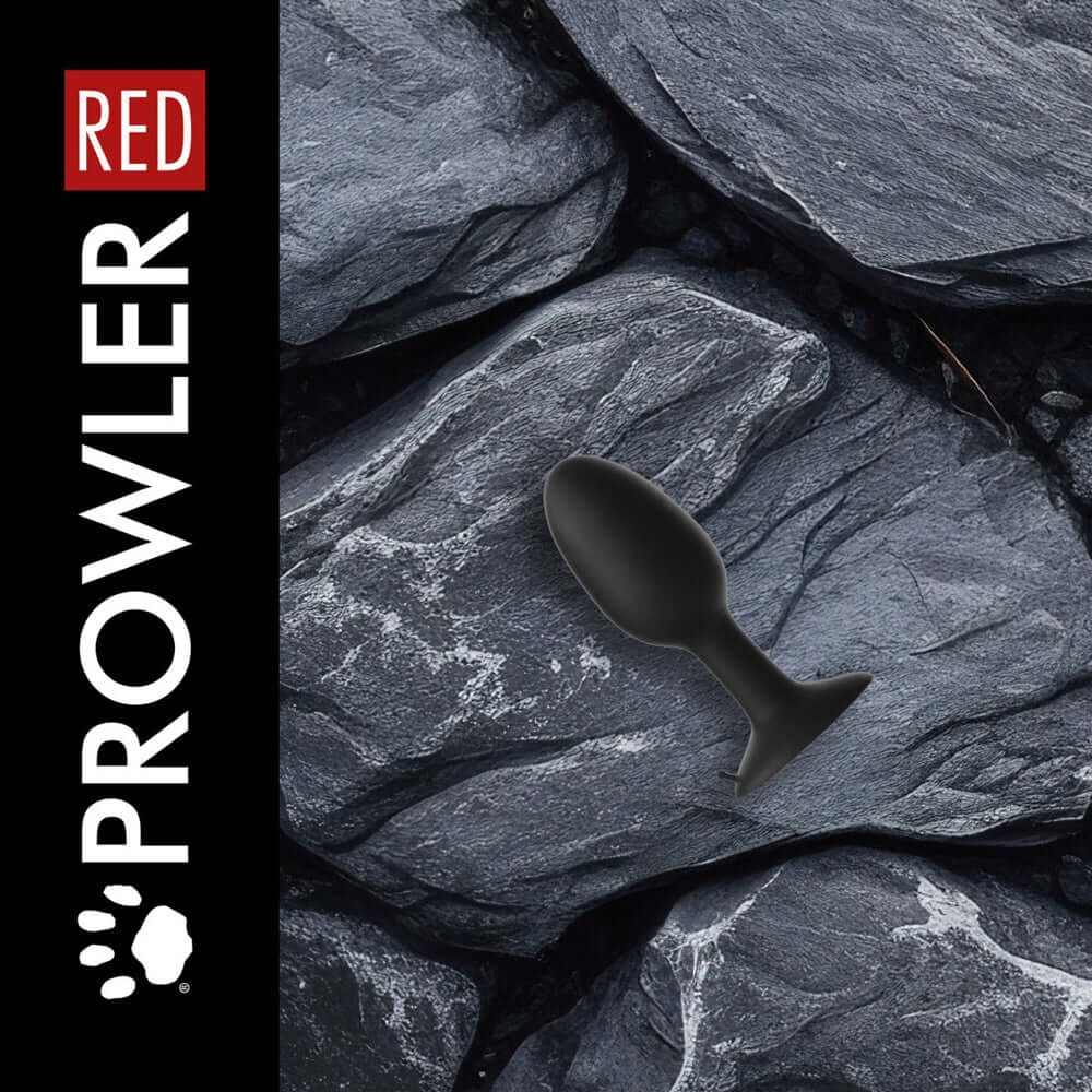 Prowler RED Weighted Butt Plug Black Medium on textured rocks background.