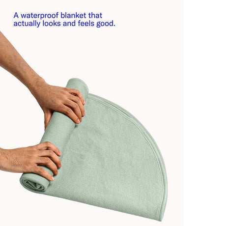 Dame Thro Waterproof Sex Blanket Sage rolled up in soft fabric, showcasing its elegant design and functionality.