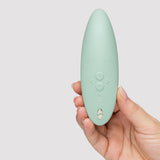 We-Vibe Melt 2 Pleasure Air Clitoral Stimulator Sage held in hand, showcasing its sleek design and buttons.