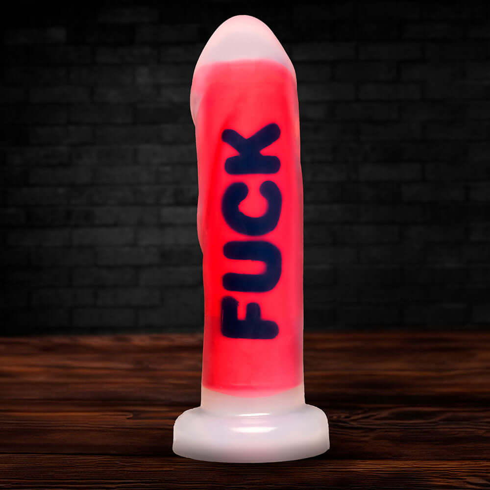 Master Series FUCK Silicone Dildo displayed on a wooden table against a dark background.