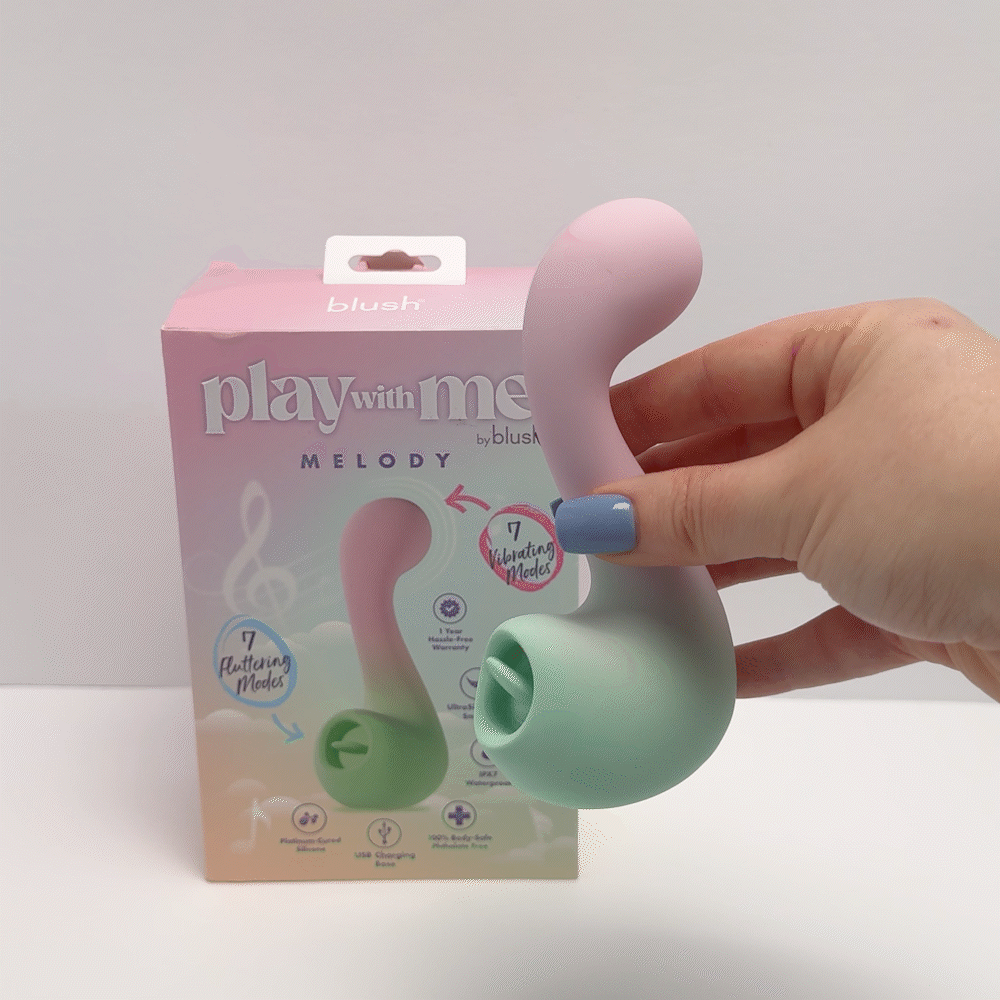 Hand holding Play With Me Massager Melody Pink toy beside the product packaging featuring playful design.