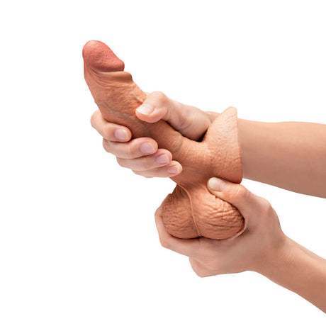 b-Vibe Slipskin Realistic Silicone Dildo 6 inch Girthy Mocha being squeezed in hands, showcasing its lifelike design.